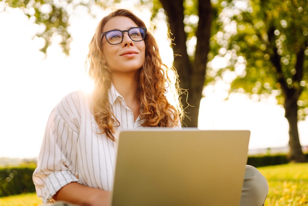 Young,Woman,Working,On,A,Laptop,Outdoors,In,A,Sunny